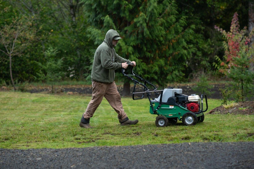 Adam Todd running a walk-behind aerator along a residential lawn