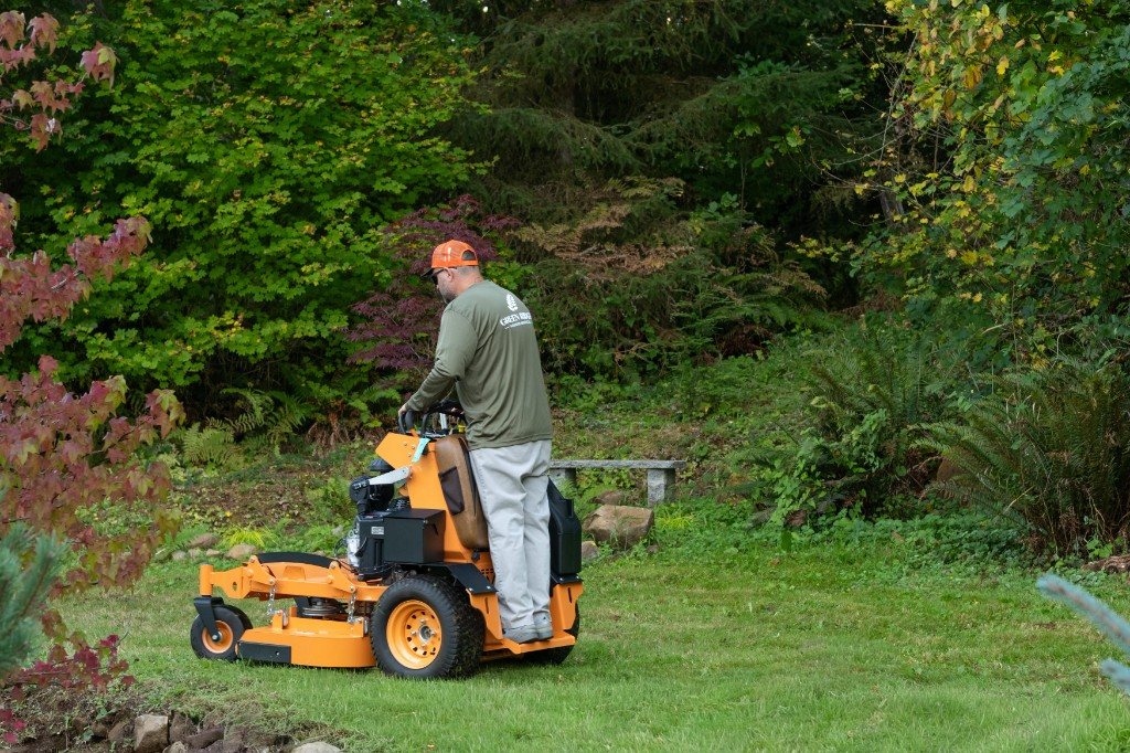 Adam Todd mowing a lawn on a stand-on mower for Green Ridge Garden Services